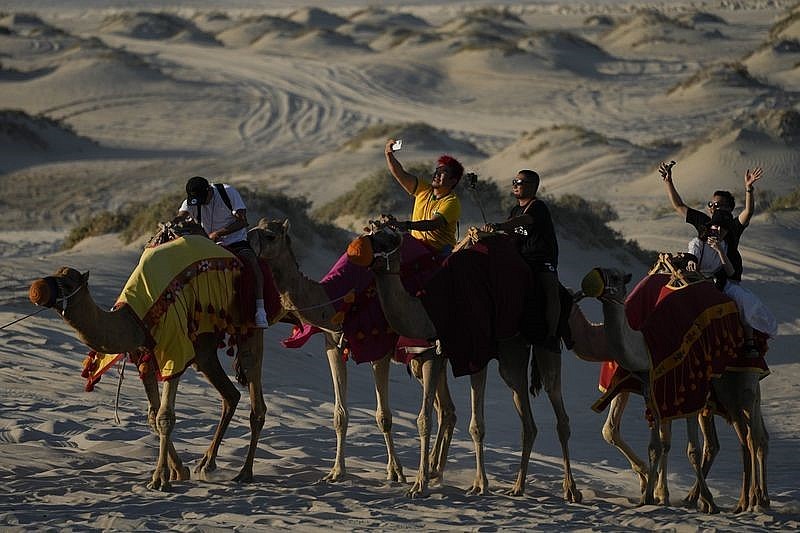 (Những du khách chụp ảnh khi ngồi trên lưng lạc đà – Nguồn ảnh: Ashley Landis/AP)