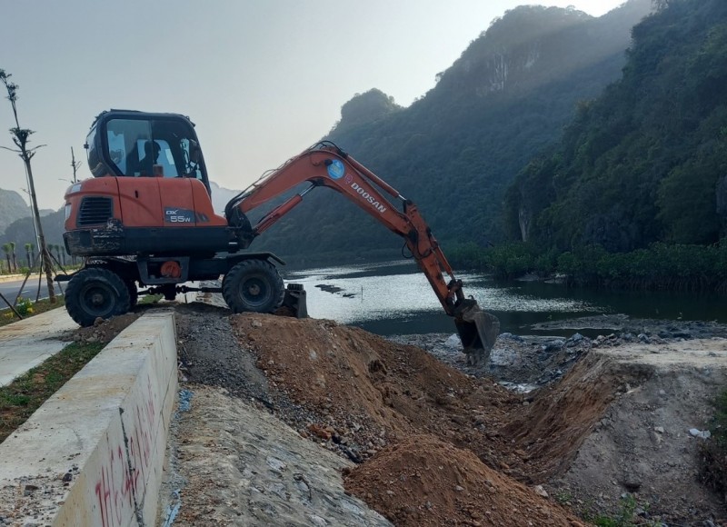 Chính quyền phường đang sử dụng máy cẩu phá dỡ đường dẫn tự phát để khơi thông dòng nước vào rừng ngập mặn. Ảnh: UBND phường Quang Hanh.