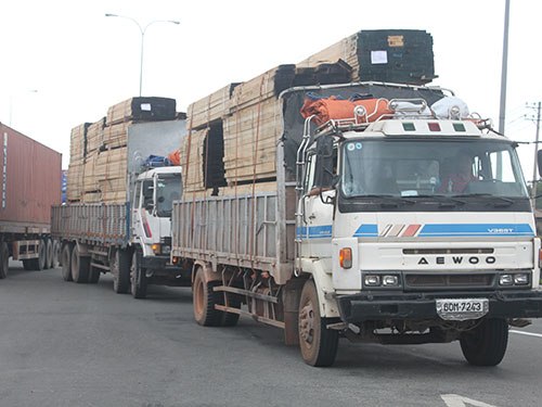 Hai xe tải chất gỗ cao hơn thùng xe lưu thông trên Quốc lộ 1A đoạn đi qua địa bàn quận Bình Tân