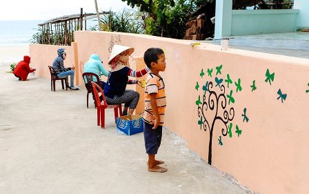 Trẻ em trong làng đang xem các họa sĩ đang vẽ