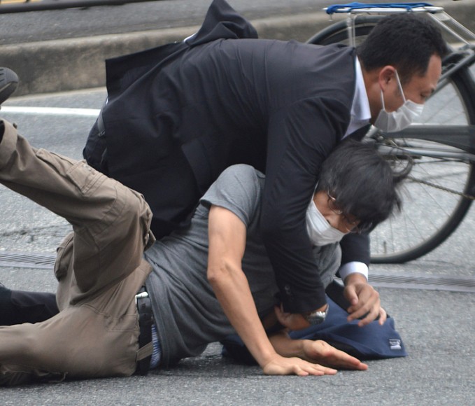 Cảnh sát khống chế nghi phạm Tetsuya Yamagami (áo xám) tại hiện trường vụ nổ súng