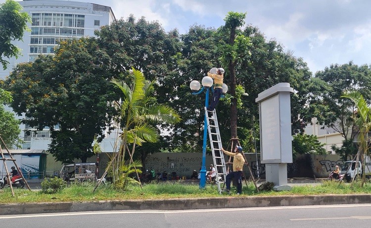 Hơn 11 giờ, nắng nóng bắt đầu gay gắt, 2 công nhân vẫn miệt mài sửa bóng đèn trên đường Hoàng Quốc Việt